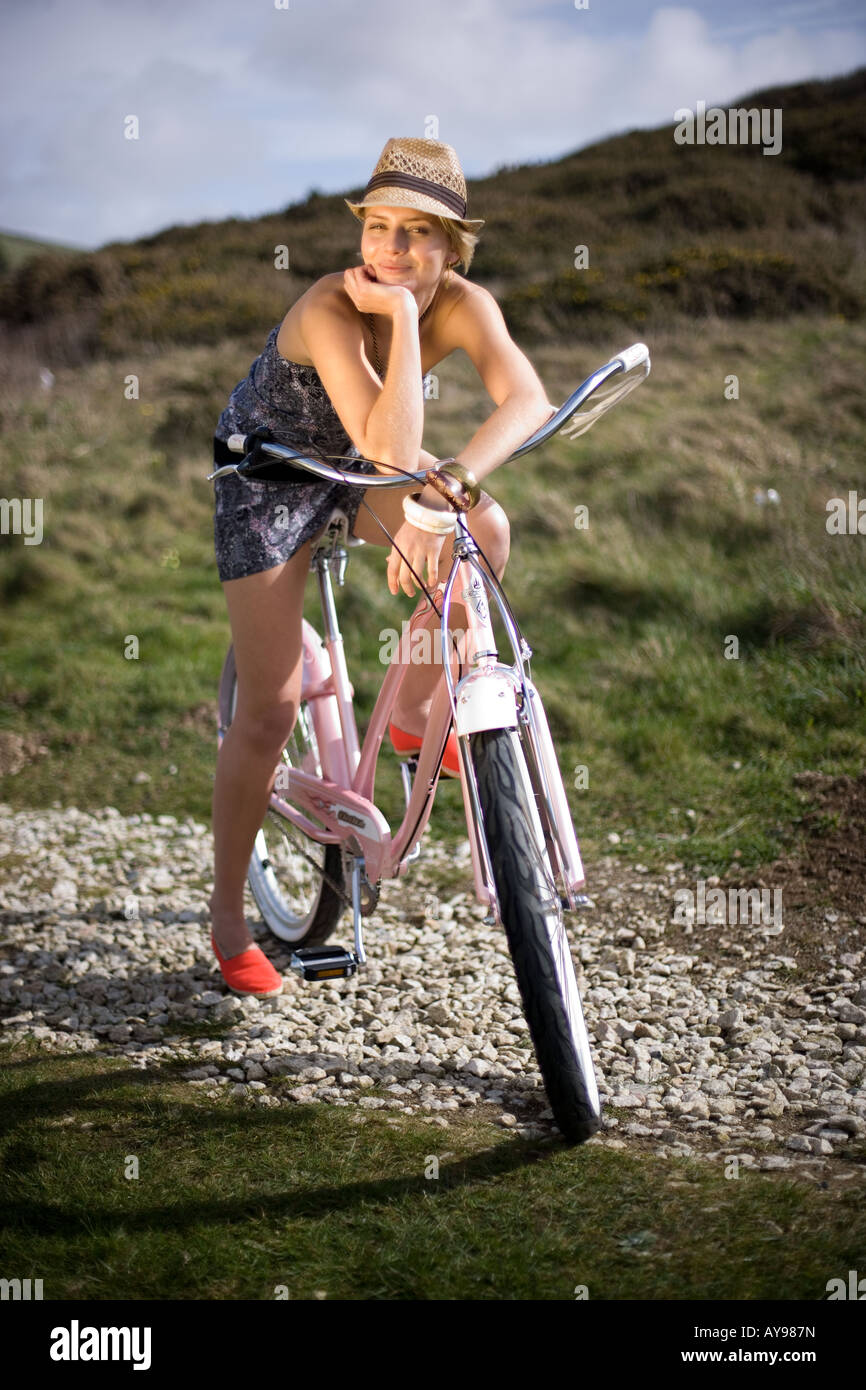 Girl on bike in strapless dress and sunhat Stock Photo