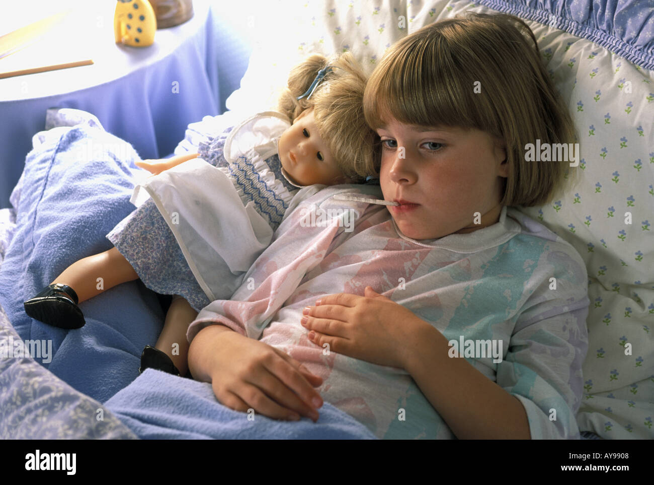 sick child in bed with thermometer Sandra favorite doll Stock Photo