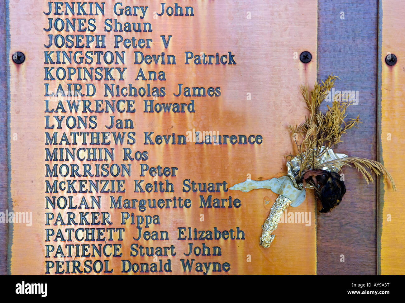 A small bouquet of dead flowers next to an old stained memorial plaque. Stock Photo