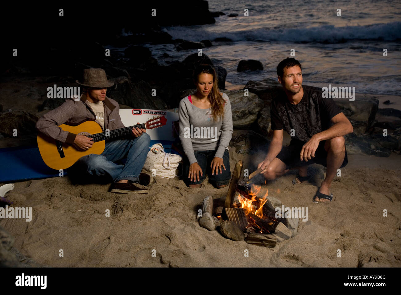 Surfers round campfire on beach, Cornwall Stock Photo