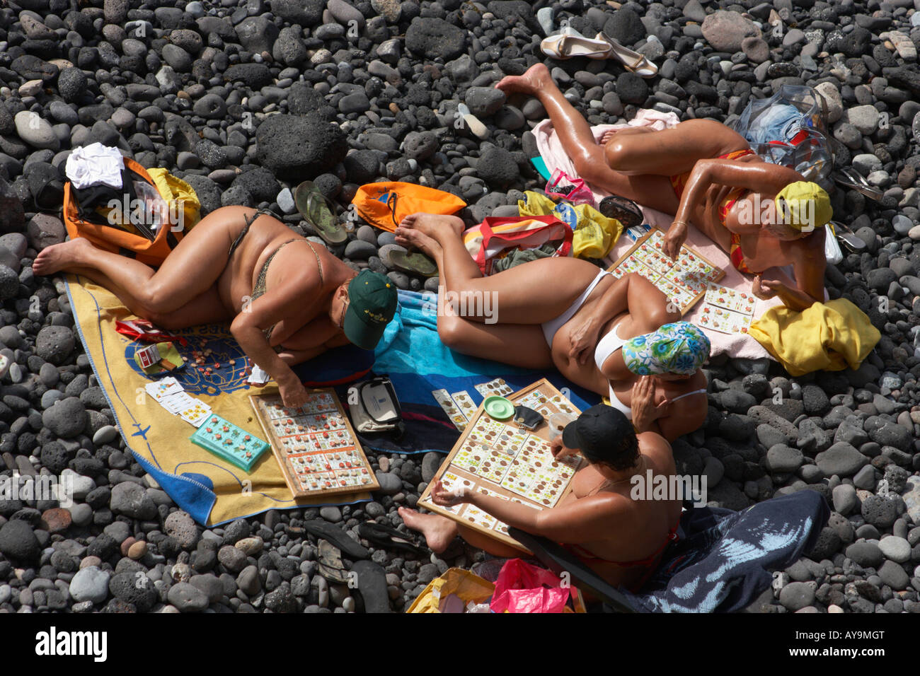 Four Spanish women playing cards and bingo on rocky beach in front of their houses on Gran Canaria Stock Photo