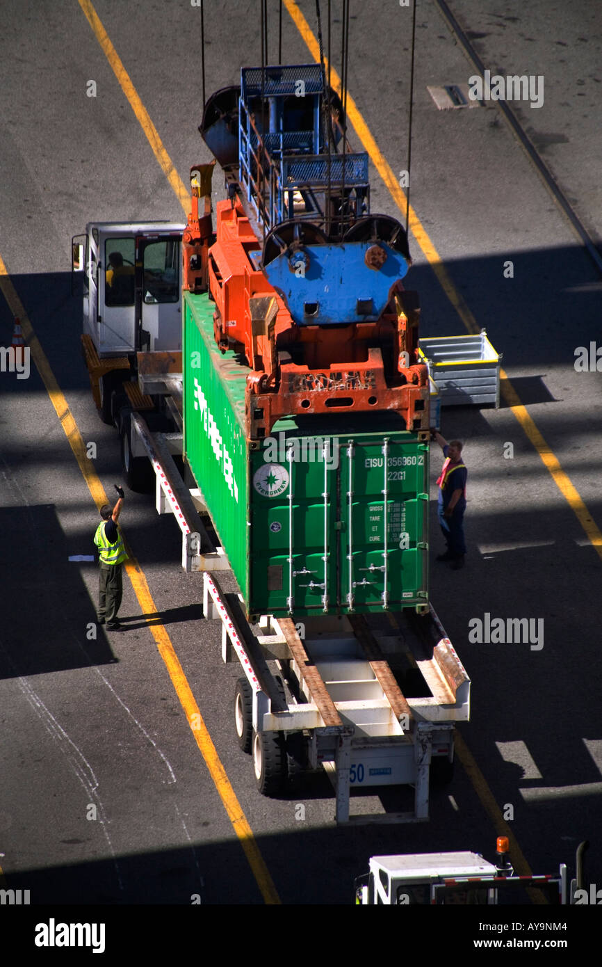 Gang longshoremen direct an overhead crane transferring cargo