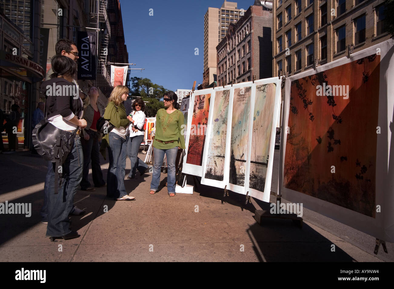 An artist converses with passersby at a Sunday sidewalk display of her work on West Broadway in the SoHo district South of Houst Stock Photo