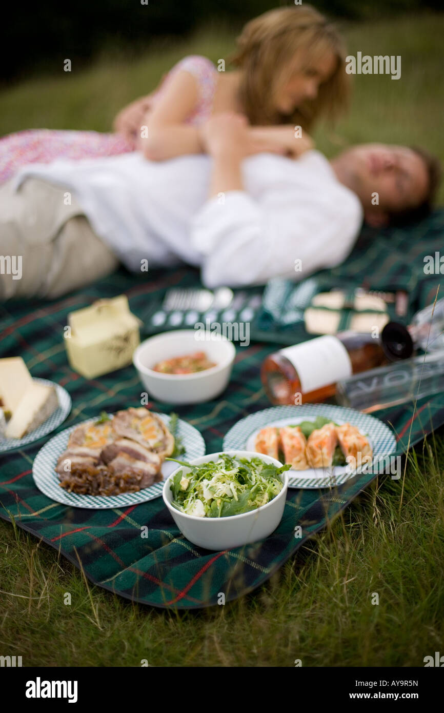 Couple lying on picnic blanket with hamper food Stock Photo