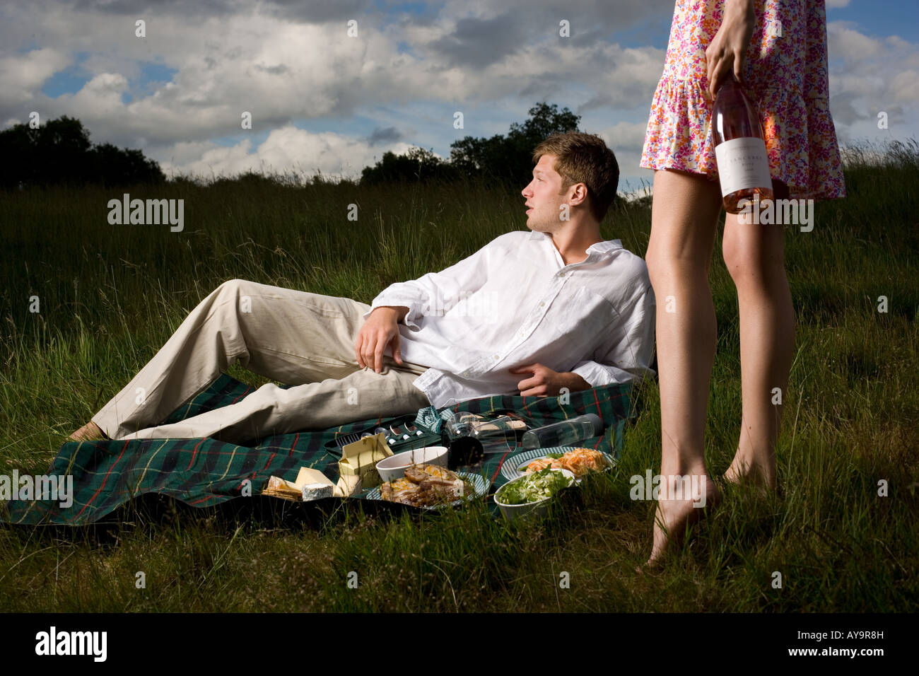 Man lying on picnic blanket with hamper food Stock Photo