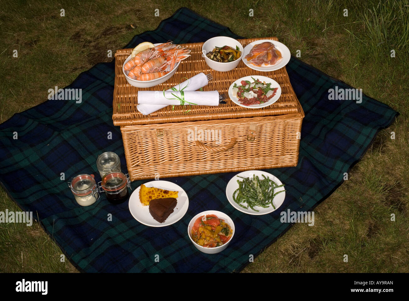 Summer picnic hamper basket with food on blanket Stock Photo