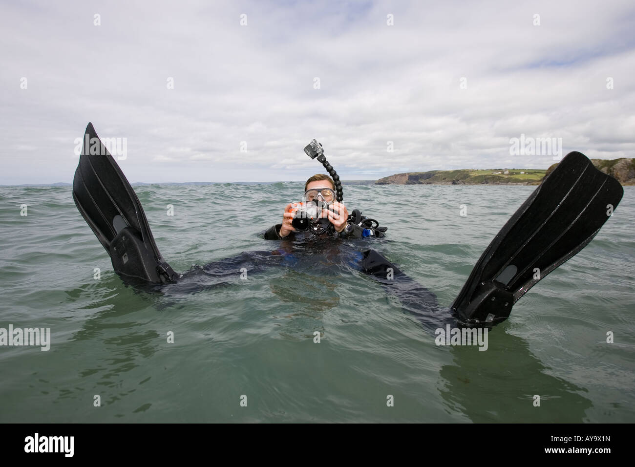 Scuba diver adjusting camera while floating on water Stock Photo