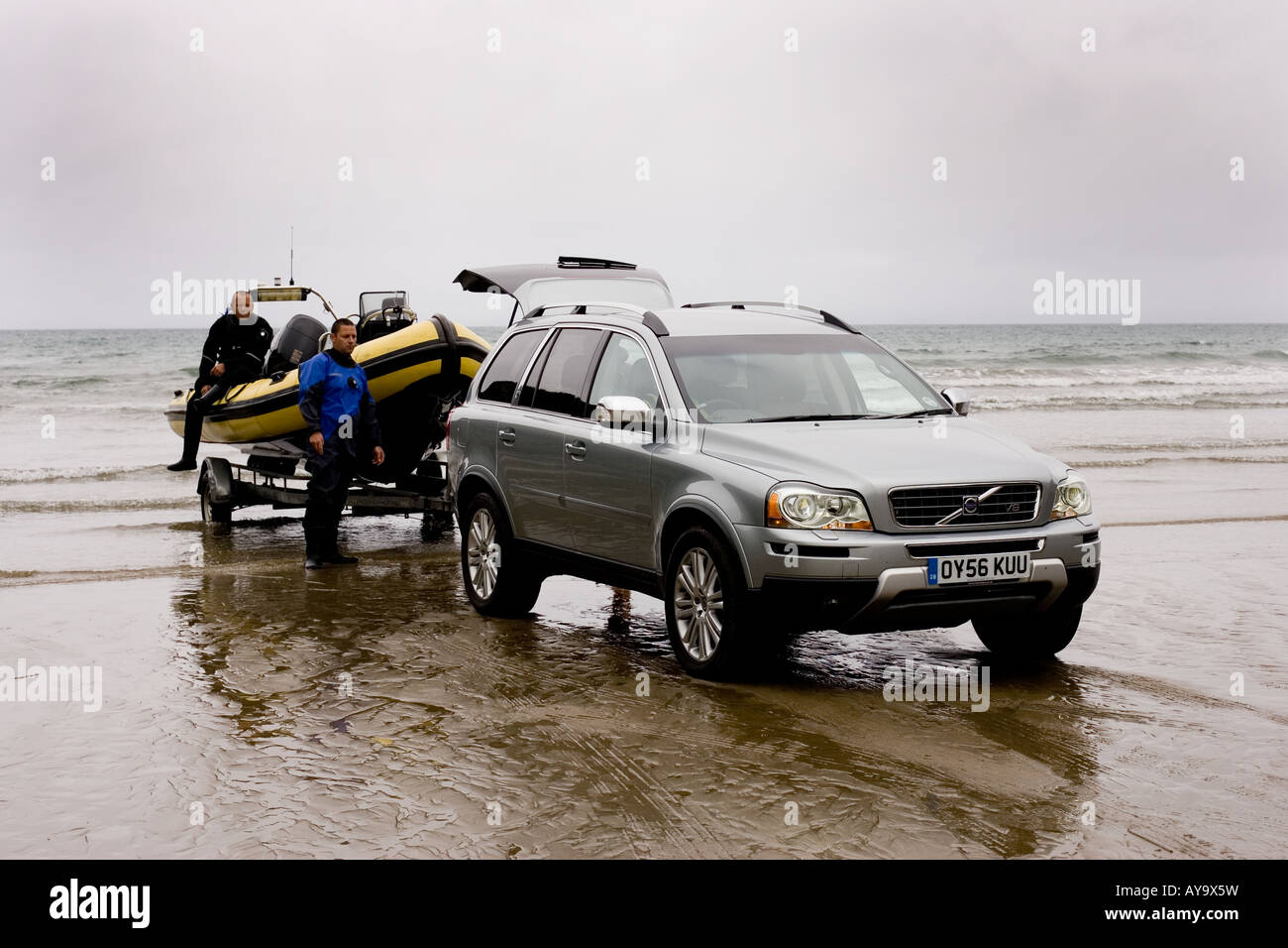 Scuba divers trailing rib boat from sea with 4x4 vehicle Stock Photo