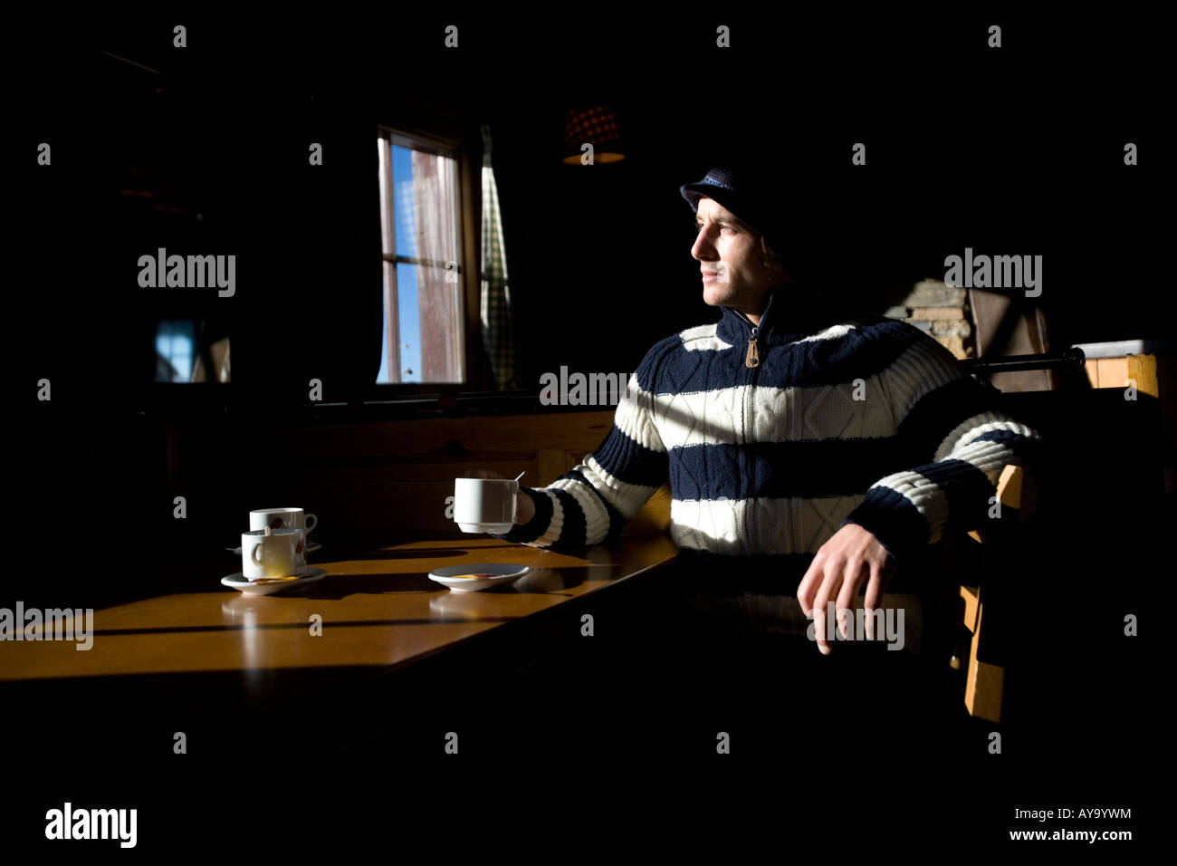 Snowboarder sitting in sunlight at table in Apres ski chalet, Tignes, France Stock Photo