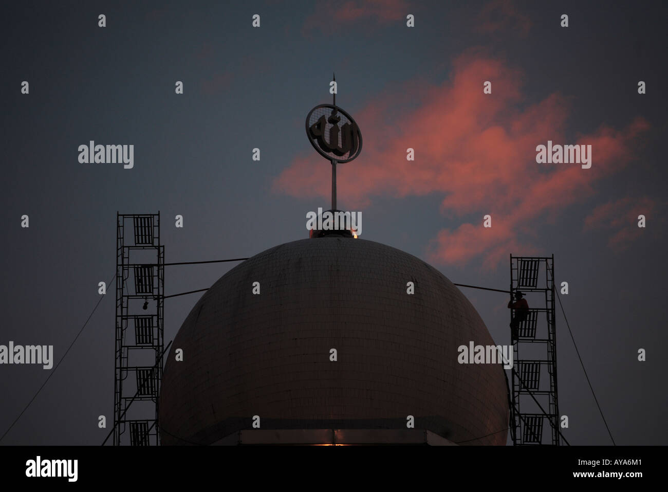 Indonesia Jakarta Workmen on scaffolding around dome of Mosque Mesjid Istiqlal at dusk Stock Photo