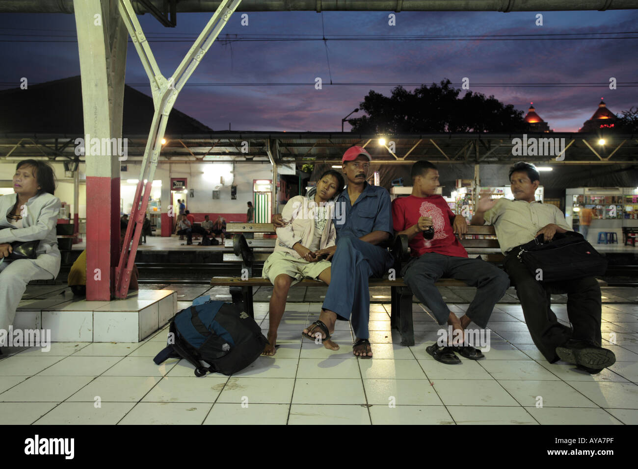 Indonesia Jakarta Young couple sitting with other passengers crowding waiting for commuter train during evening rush hour Stock Photo