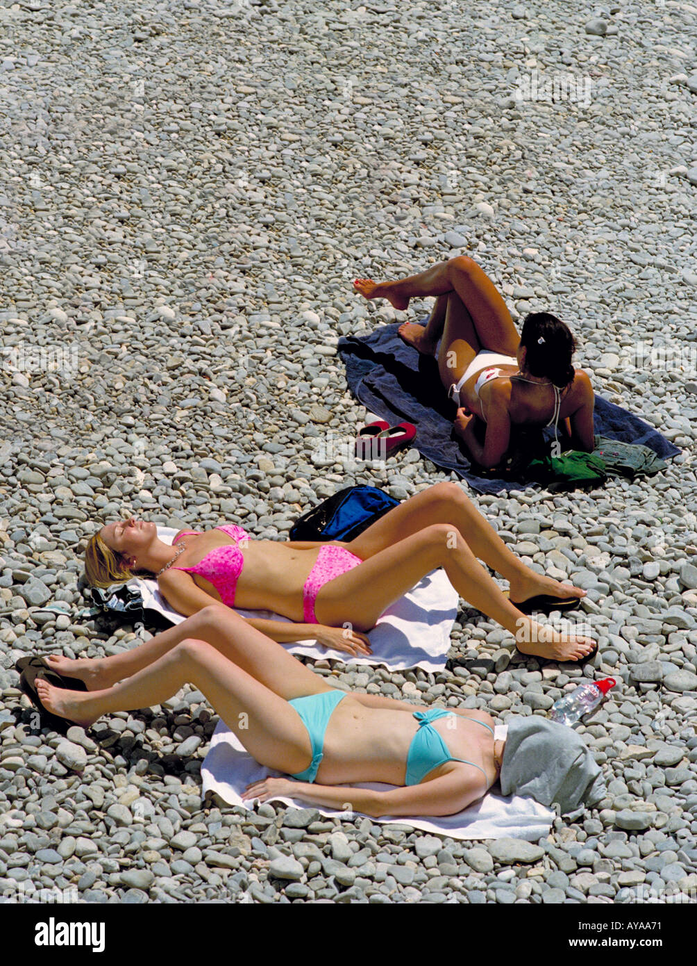 Three girls in bikinis sunbathing on the beach at Nice on the Cote d'Azur,  France. Three different shades of tan Stock Photo - Alamy