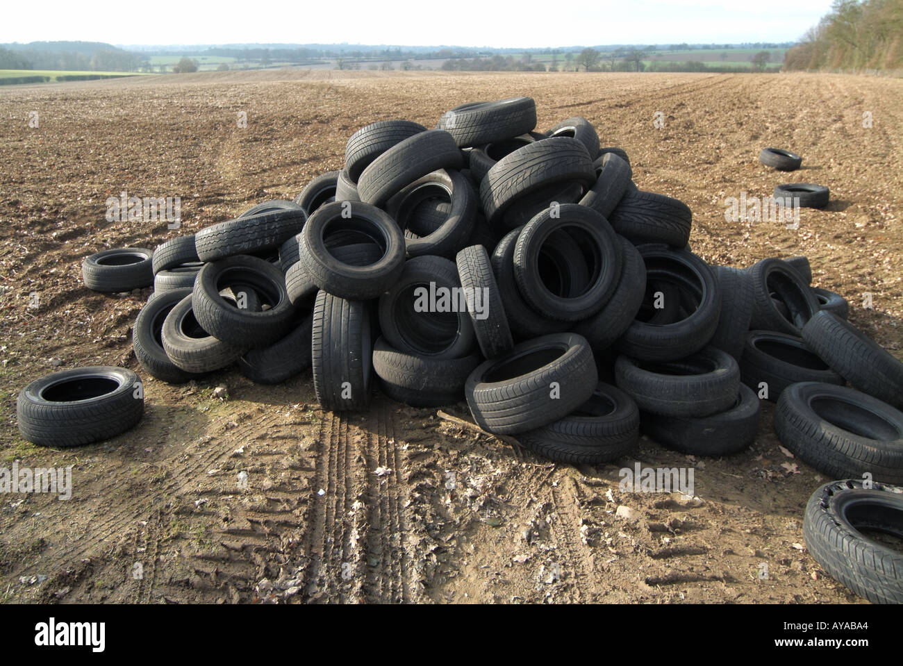 Illegal fly tipping of vehicle tyres dumped in farm field to avoid paying disposal charges flytipping big problem in countryside Essex Engalnd UK Stock Photo