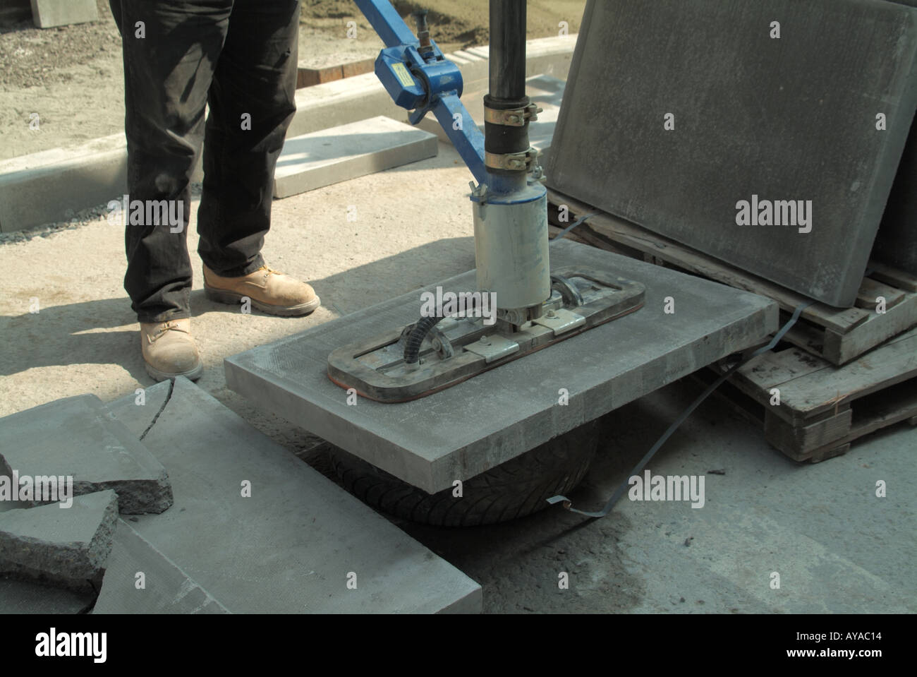 Close up of workman using a powered suction device to lift heavy street