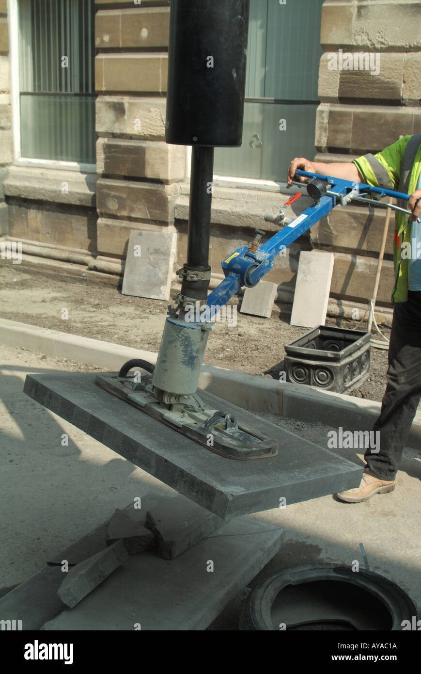 Close up of workman using a powered suction device to lift heavy street