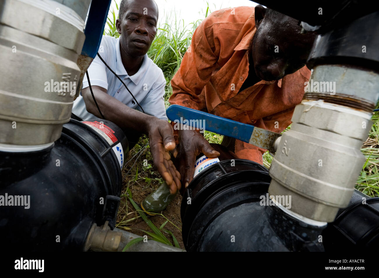 Men cleaning filter on agricultural irrigation system pump Stock Photo