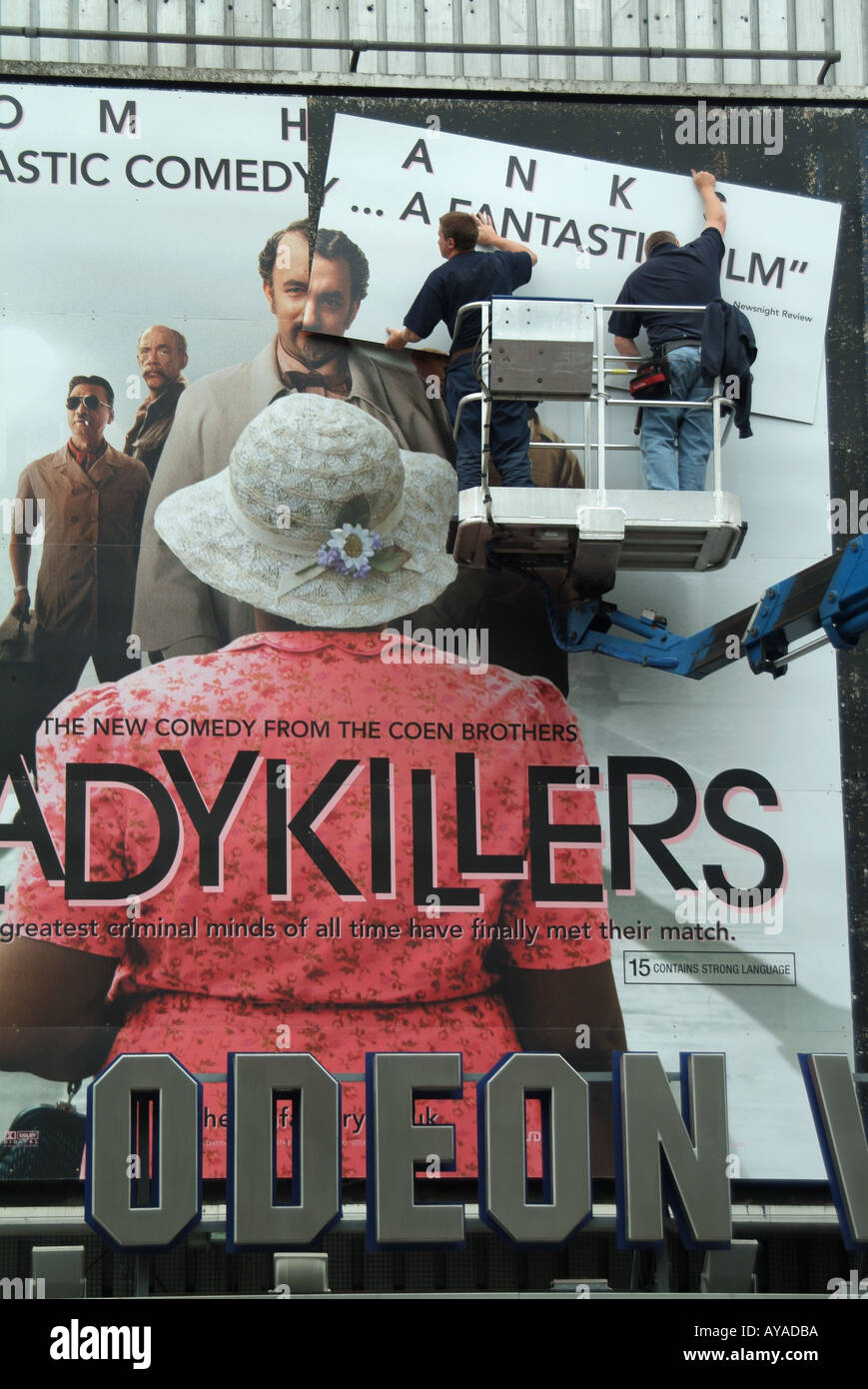 Workmen fixing panels above cinema entrance for new advert promoting next major movie film "Lady Killers" at London Leicester Square England UK Stock Photo