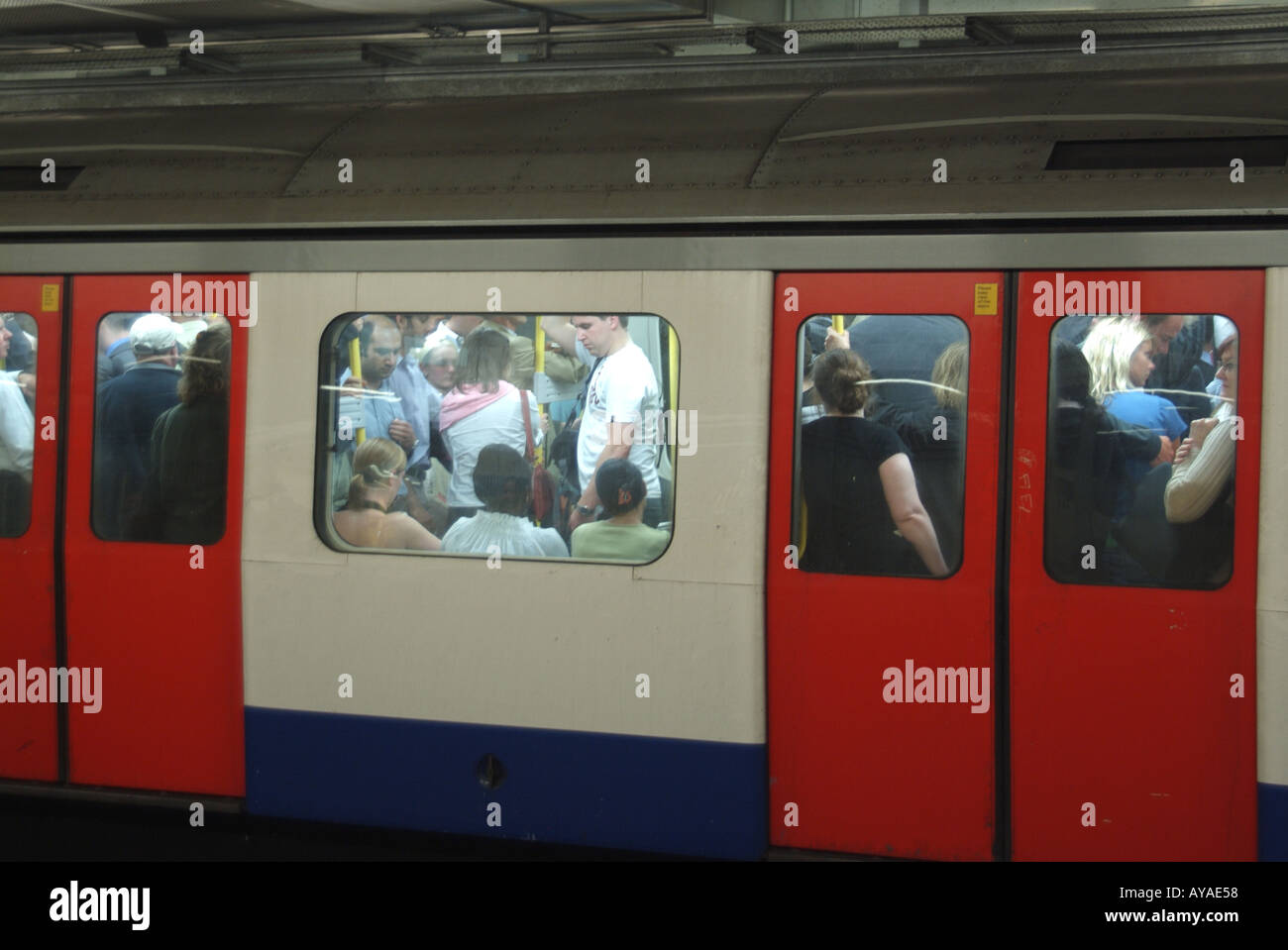 View through carriage windows standing room only in London Transport underground train crowded with evening rush hour commuters England UK Stock Photo