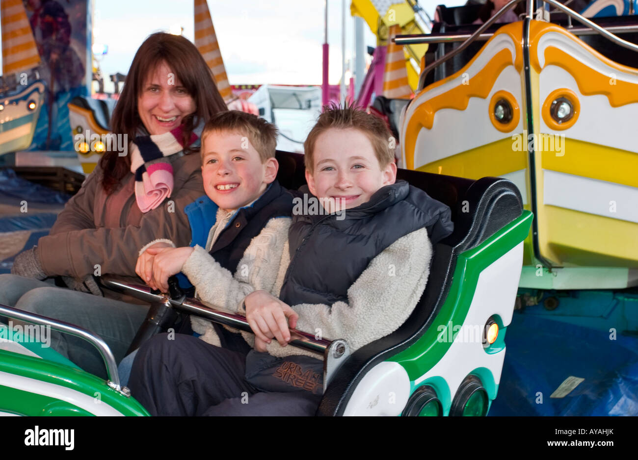 Mum and two young children on fairground ride Stock Photo