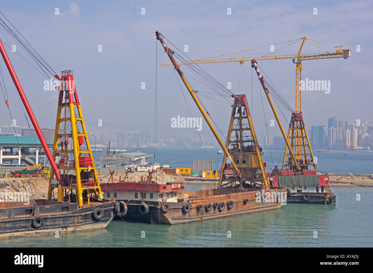 A boat mounted-crane infilling Victoria Harbour in Hong Kong, China ...