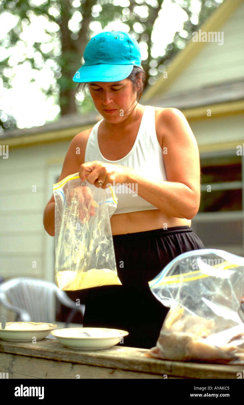 Mother age 35 breading fresh caught fish for barbecue. Clitherall Minnesota USA Stock Photo