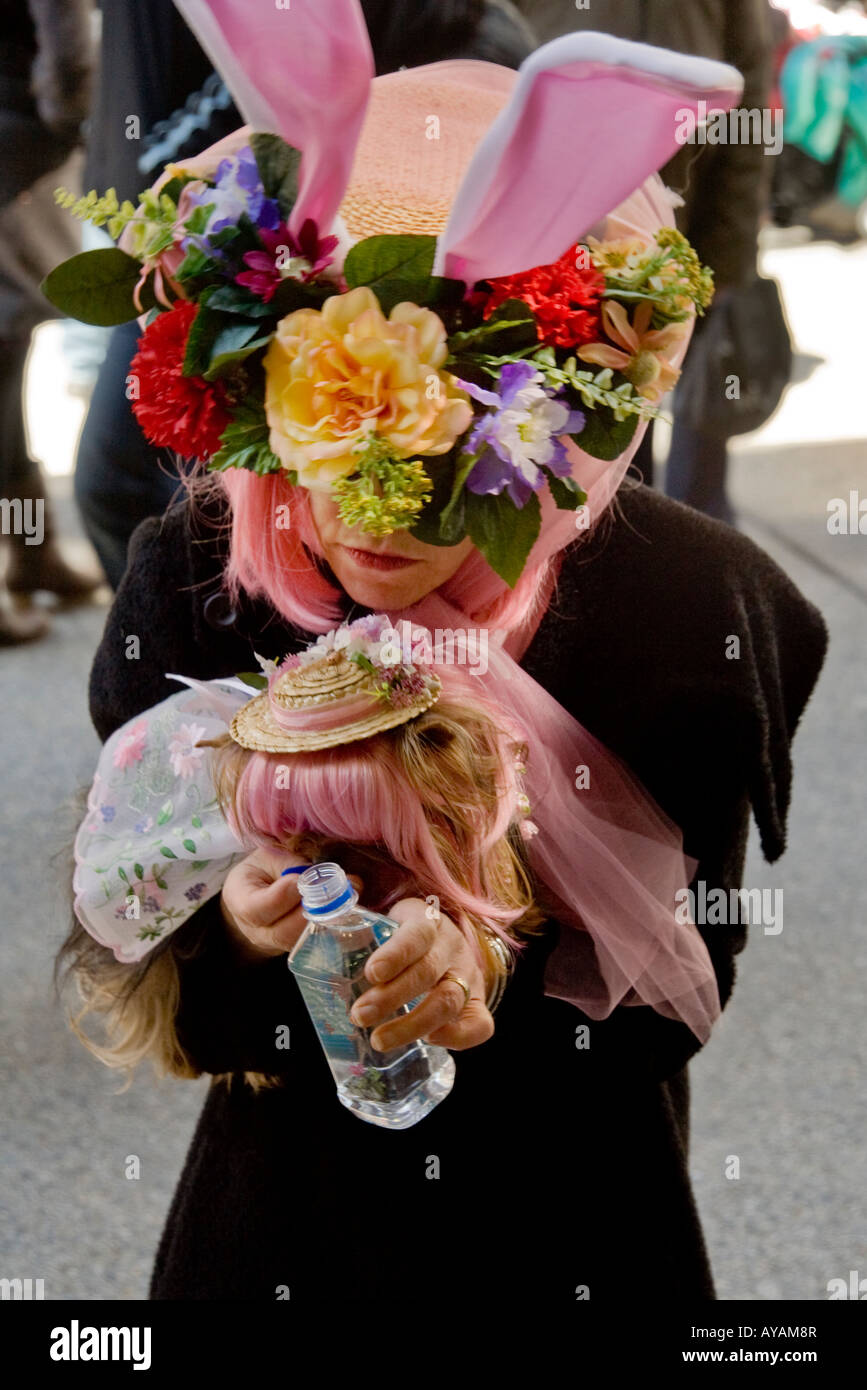 A woman in an Easter Parade crazy hat refreshes her costumed dog on Fifth Ave in New York City Stock Photo