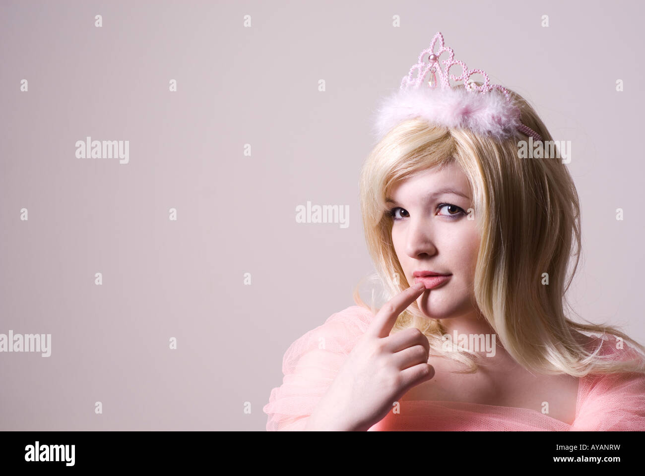 Beautiful woman in pink wearing a tiara finger on lips Stock Photo