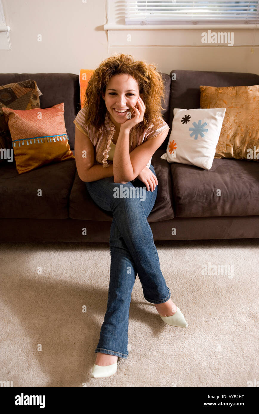 Portrait of a smiling young woman sitting on sofa Stock Photo - Alamy