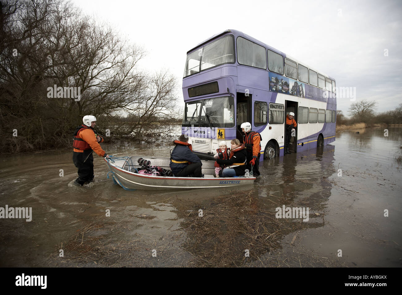 Rescue workers ferrying passengers in a boat from a bus trapped in ...
