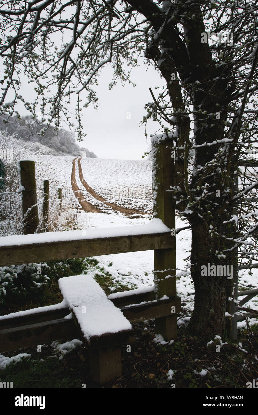 In Winter weather a stile leading to a public footpath crossing a snow covered landscape in the Chilterns Buckinghamshire UK Stock Photo