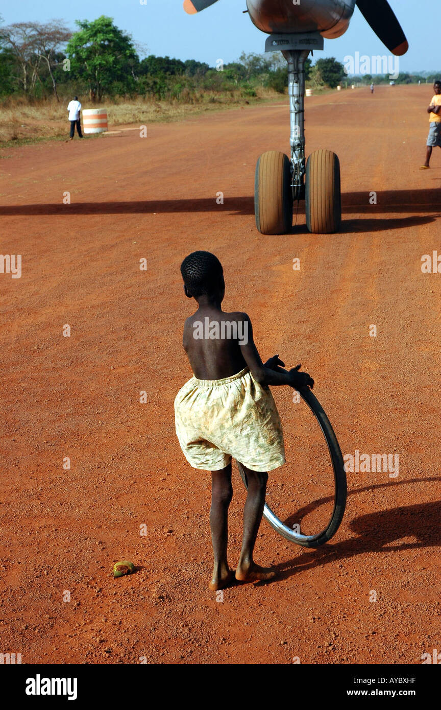 A young boy plays in the airstrip just after a big plane has landed Stock Photo