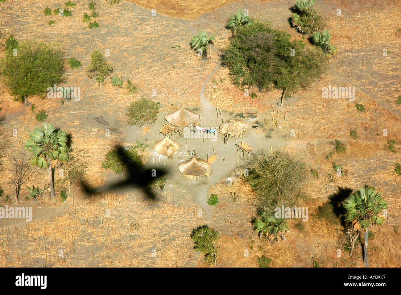 A plane casts its shadow over the inhabited traditional huts in South Sudan Stock Photo
