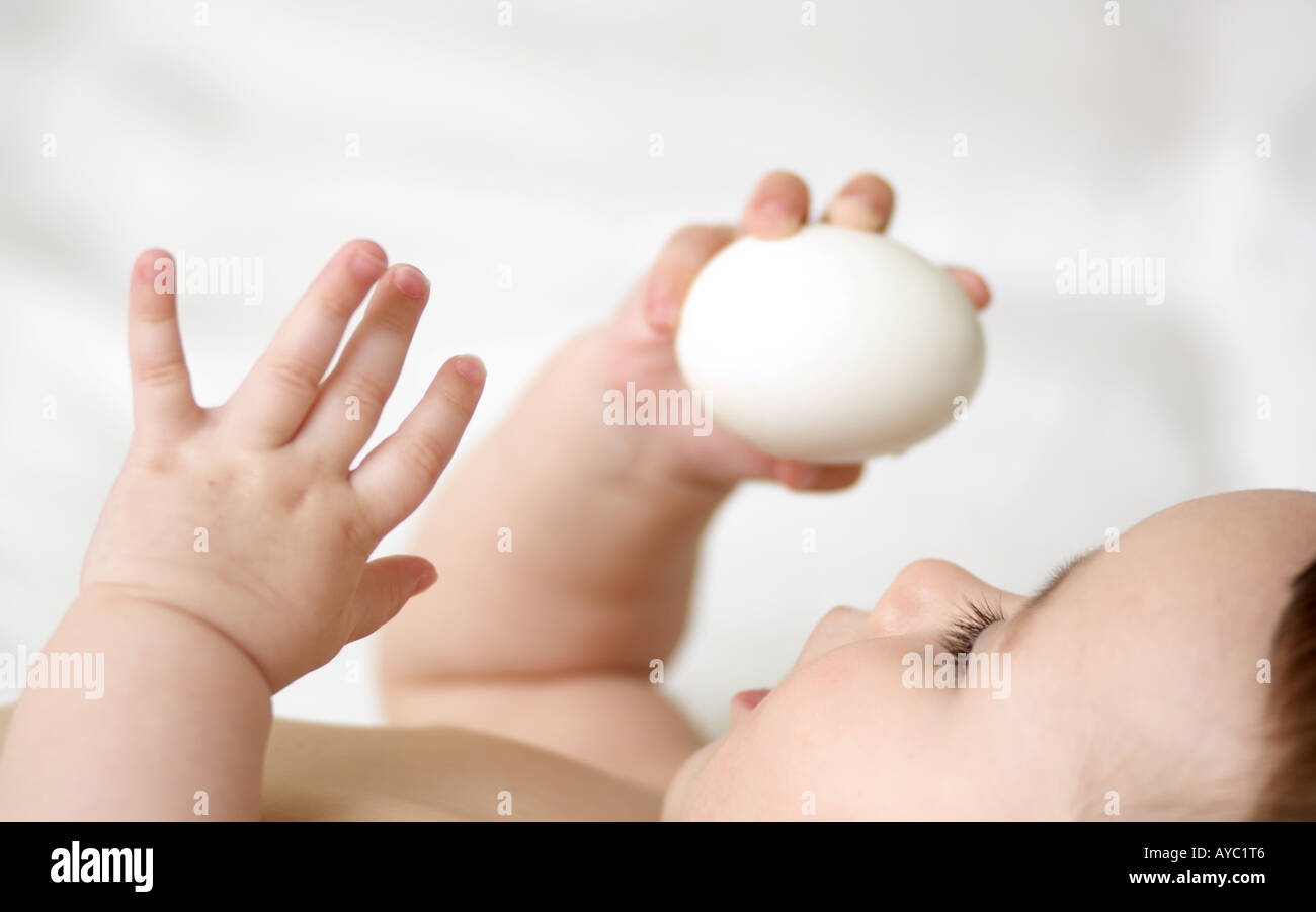 6 month old caucasian baby girl playing with egg Stock Photo