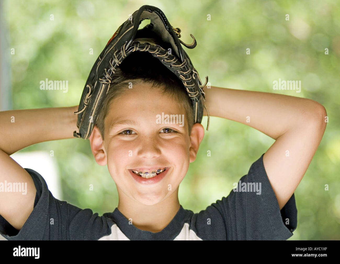 Smiling boy wearing baseball glove on his head Stock Photo Alamy