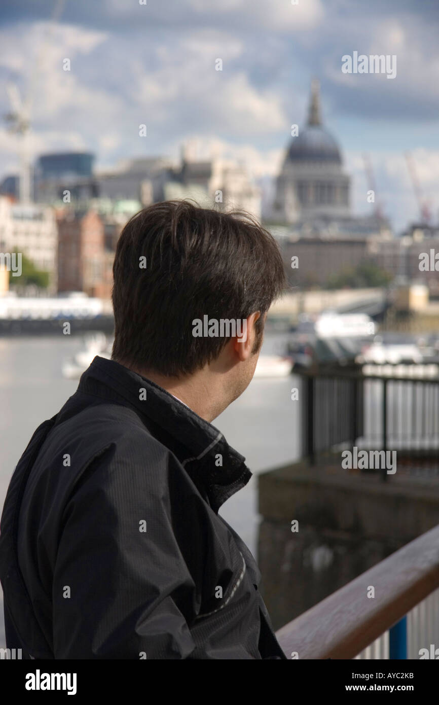 Back view of a man looking across the River Thames at St Pauls Cathedral in London, UK Stock Photo