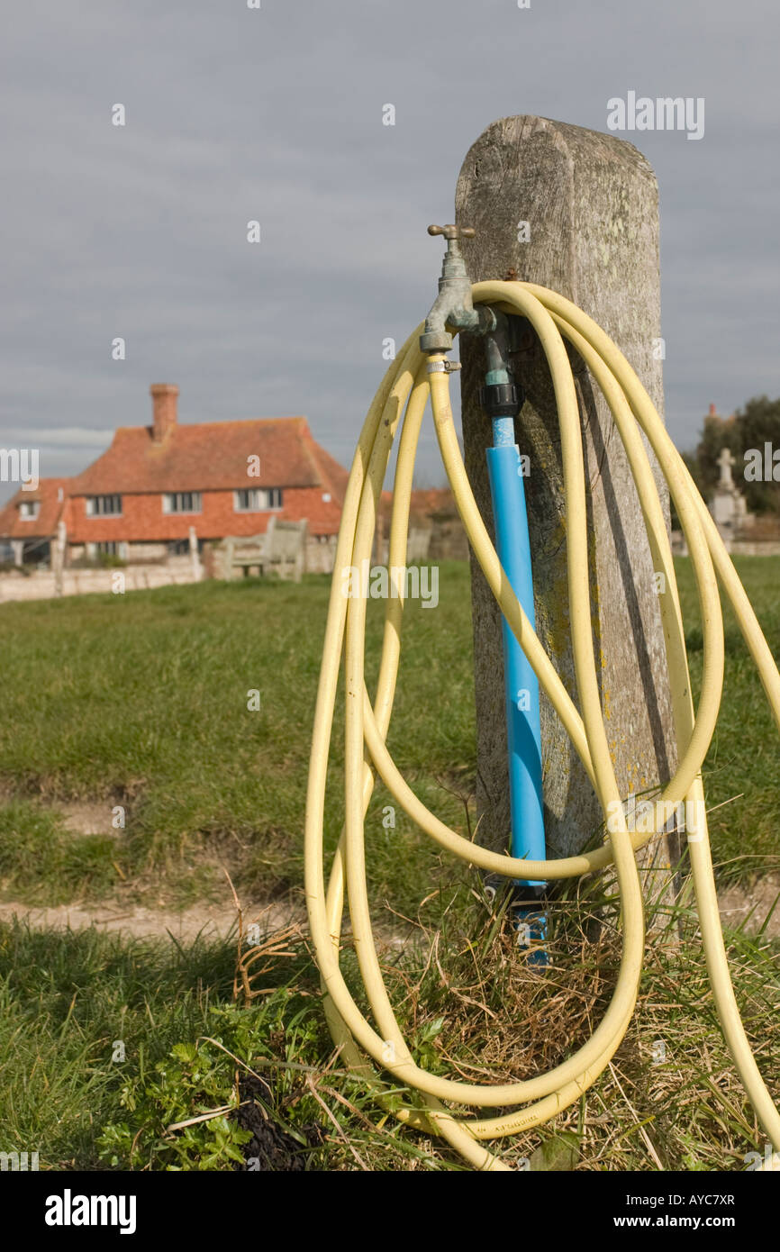 Coiled yellow hosepipe coming from Standpipe at Boshams Quay Meadow Stock Photo