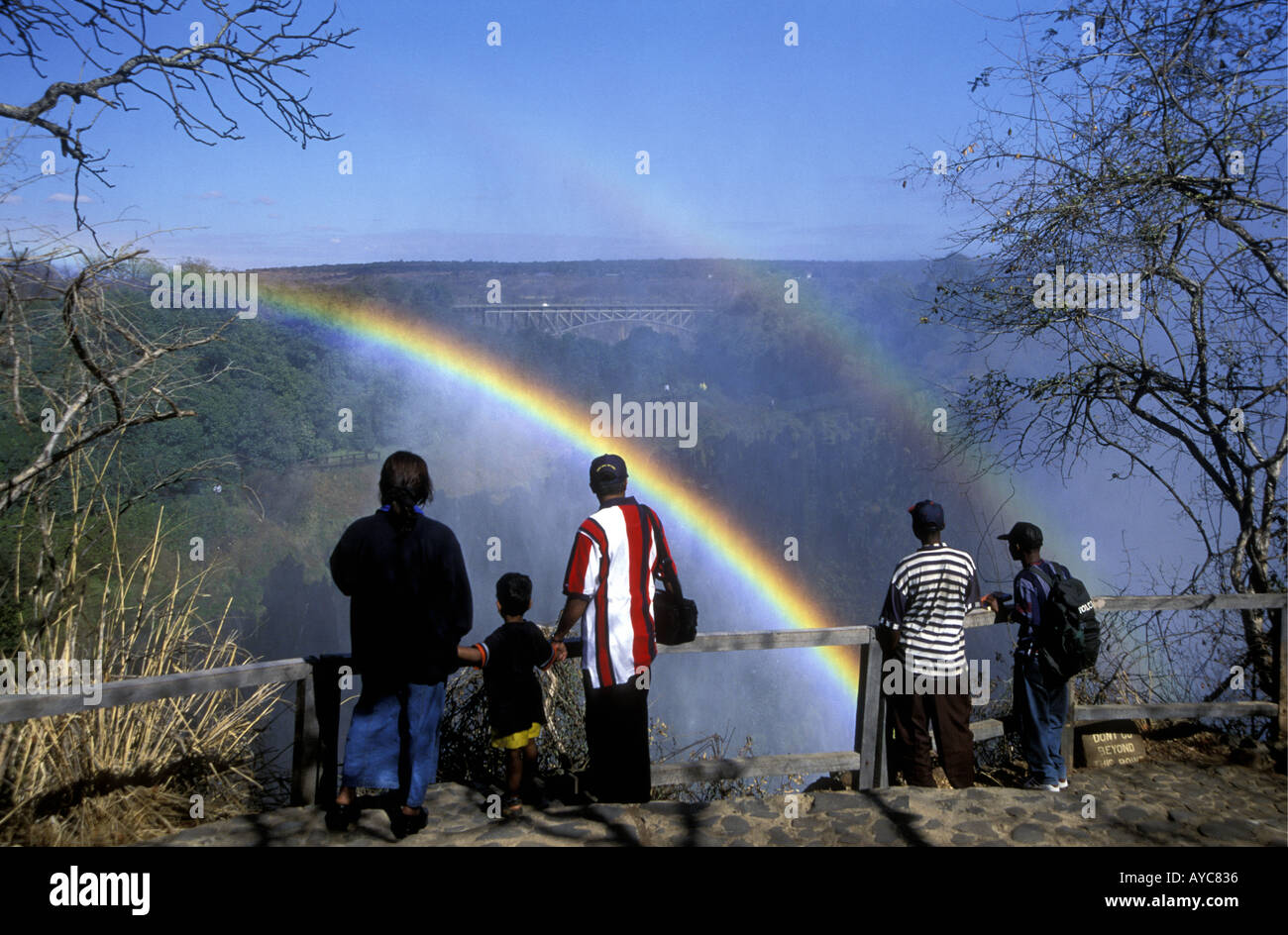 People enjoy looking at the double rainbow in the spray of Victoria Falls from the Zambia side Africa Stock Photo