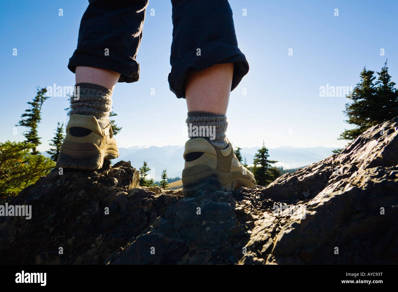 Low angle view of womans legs and shoes standing on top of a rocky outcrop on Hurricane Ridge in Olympic National Park Stock Photo