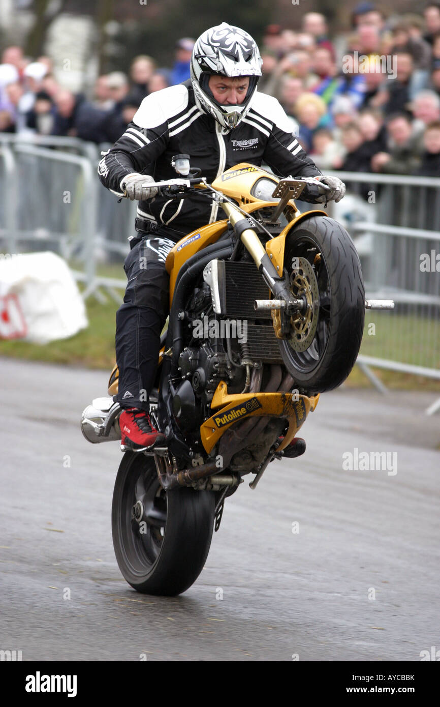 a stunt rider wheelies his triumph motorcycle during a stunt show Stock