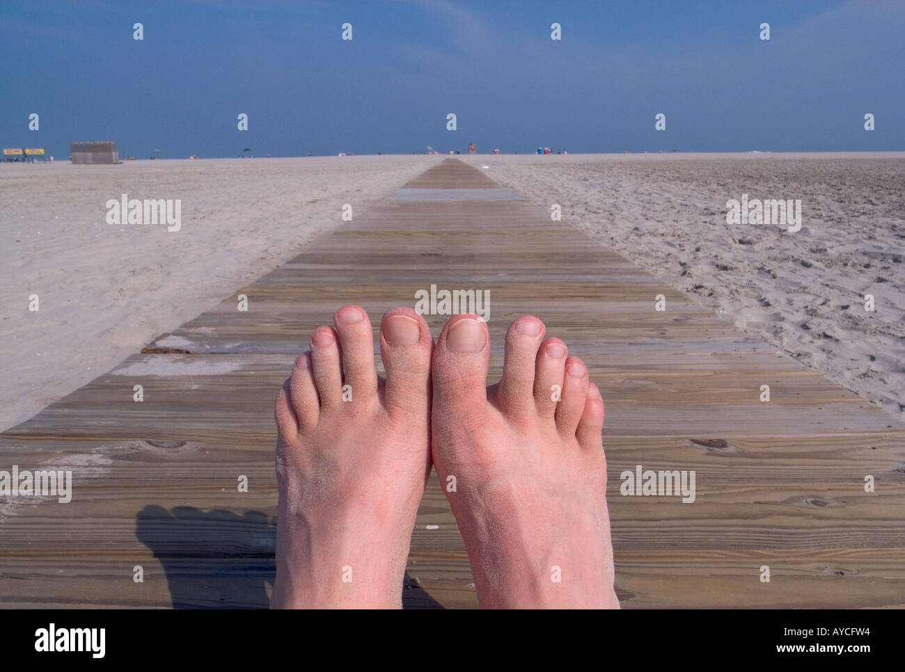 Feet in foreground on a boardwalk summer concepts male relaxing at beach Stock Photo