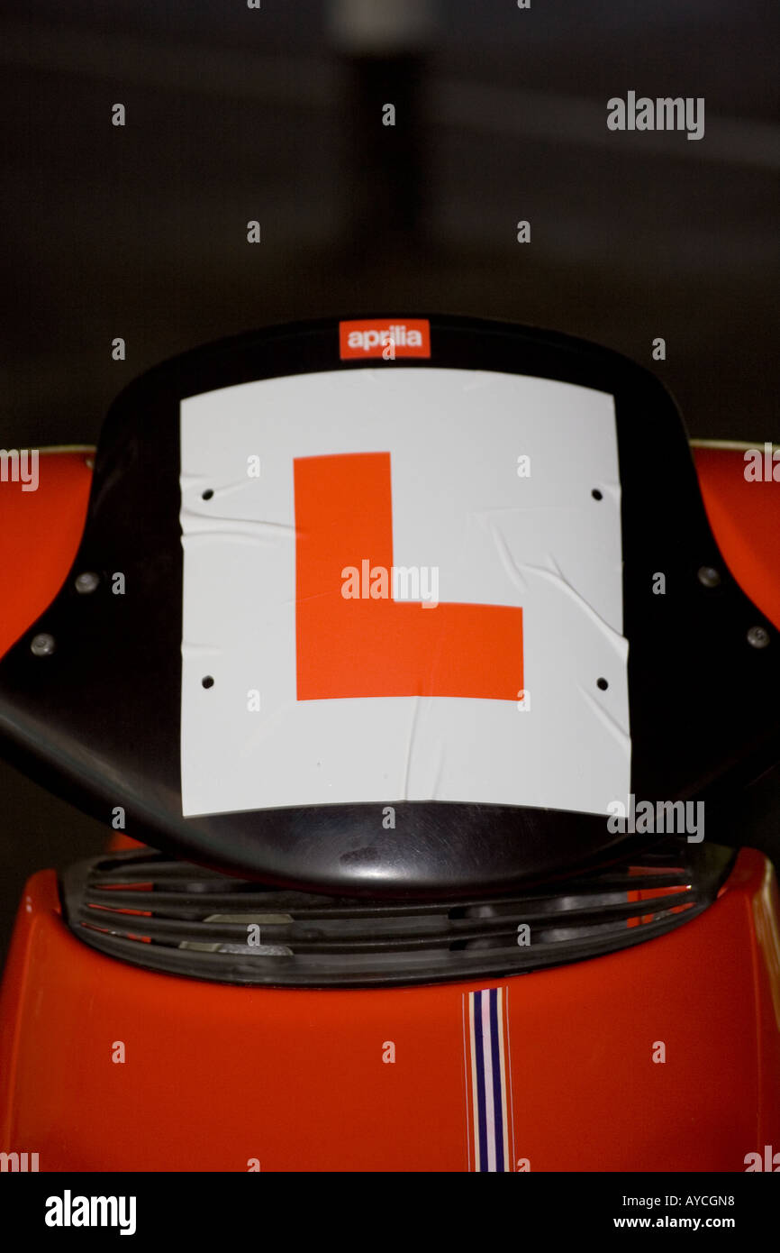 Closeup of an 'L' sticker for a learner stuck on the front windscreen of a red scooter in Dundee, UK Stock Photo