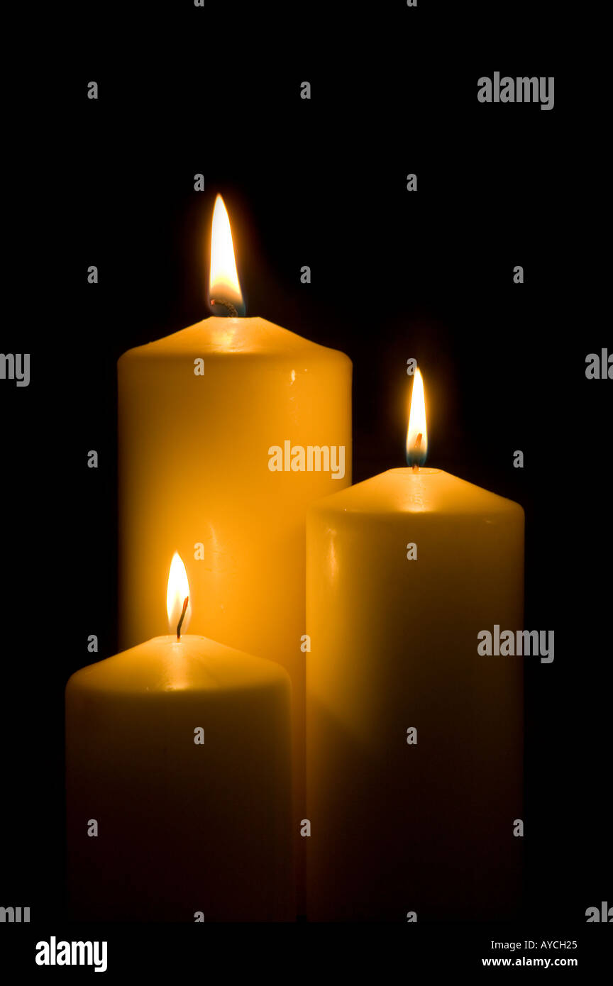Three candles burning against a black background Stock Photo - Alamy