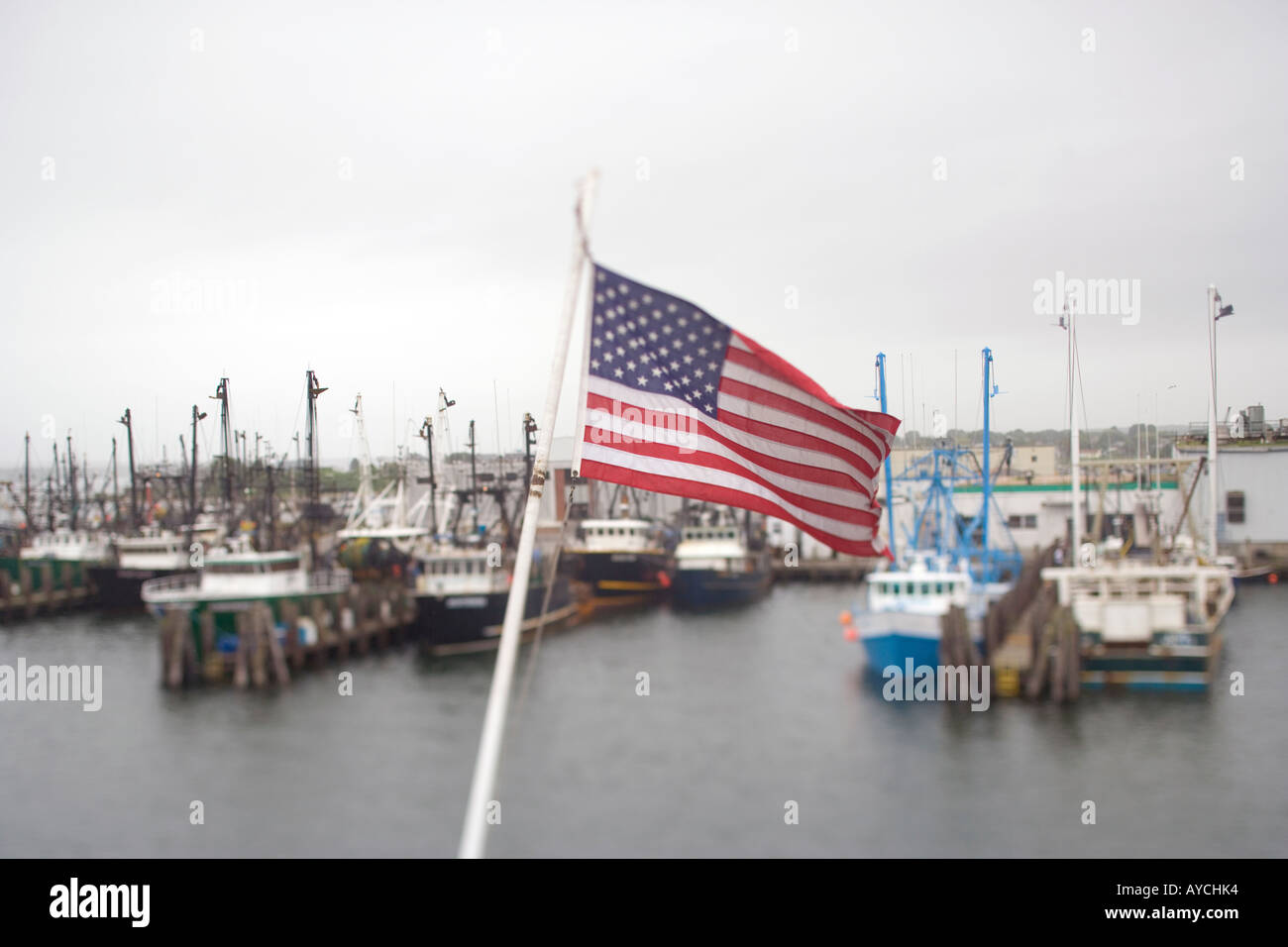 American Flag over fishing port with boats and docks in New England