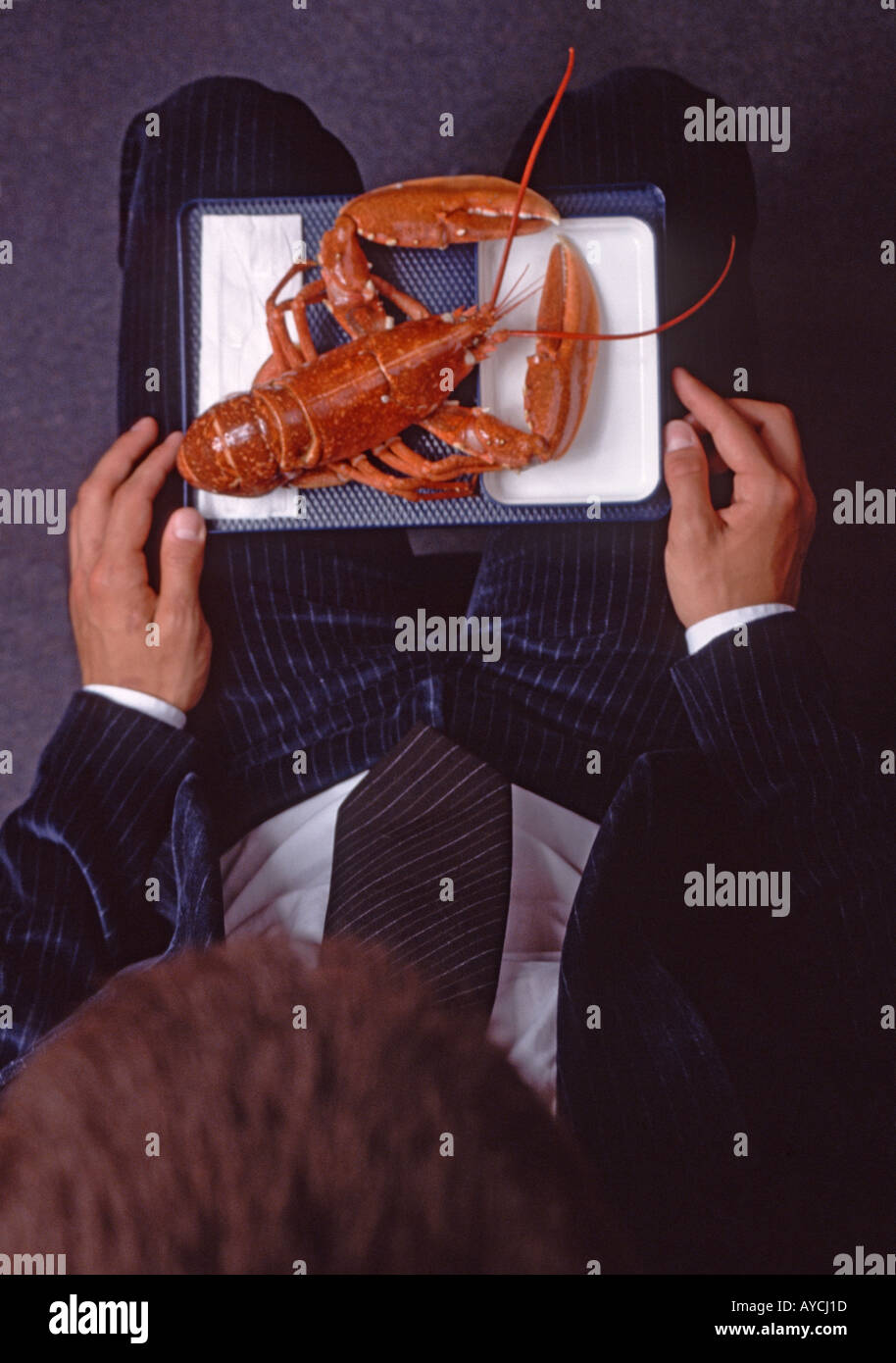 businessman sittin in an aircraft seat eating a lobster Stock Photo
