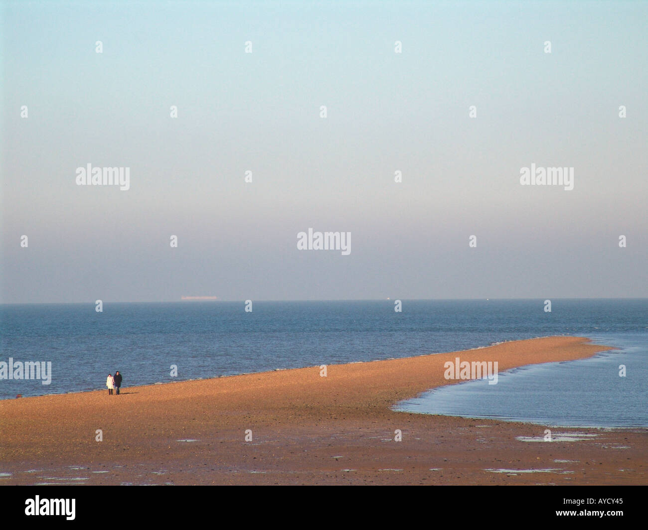 a couple  in the distance walks on the beach at tankerton  kent england uk Stock Photo