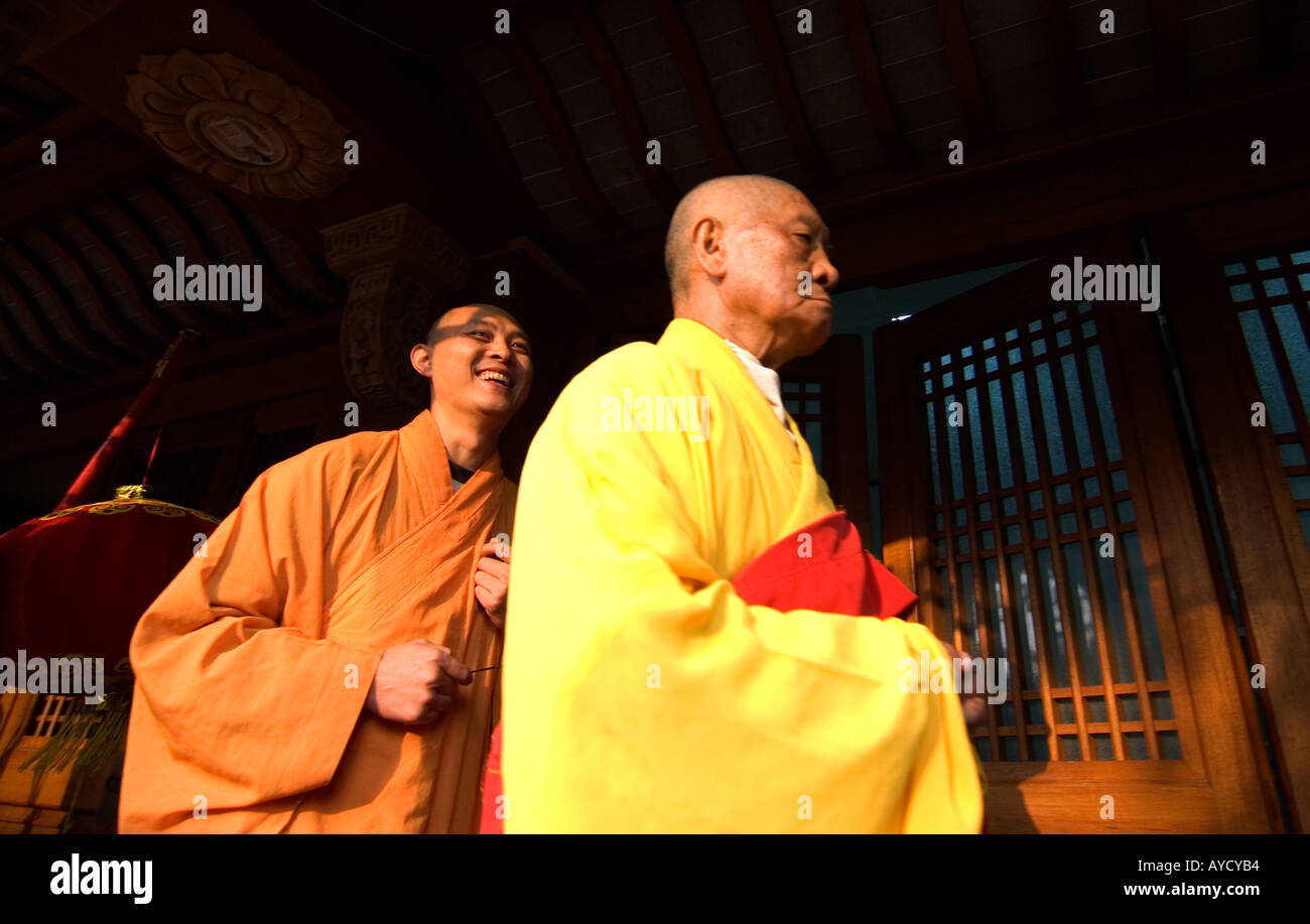 Old serious monk marching with a young laughing Buddhist monk, during a religious procession at Jingan Temple,in Shanghai, China Stock Photo