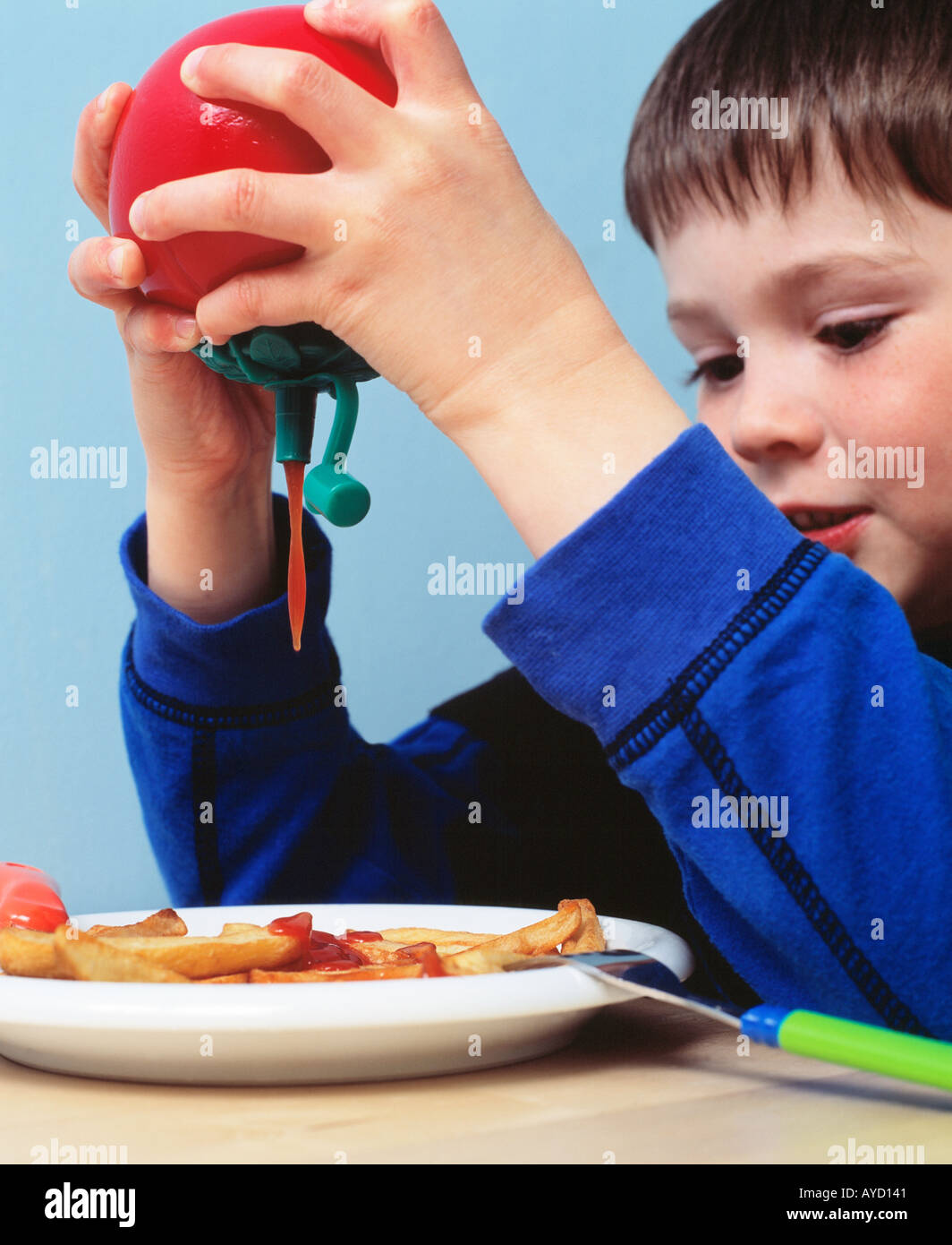 Young boy 4 6 years old pouring Tomato Ketchup on chips put putting