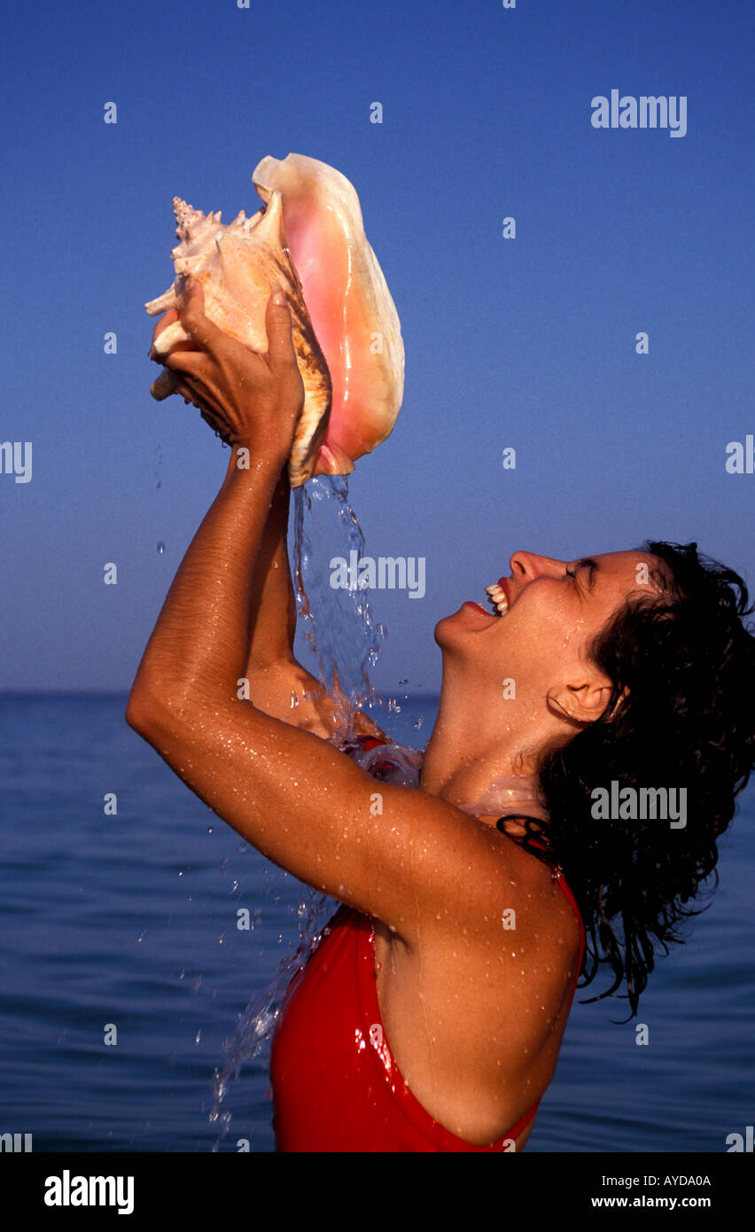 Caribbean woman holding conch shell and pouring water on self Stock Photo