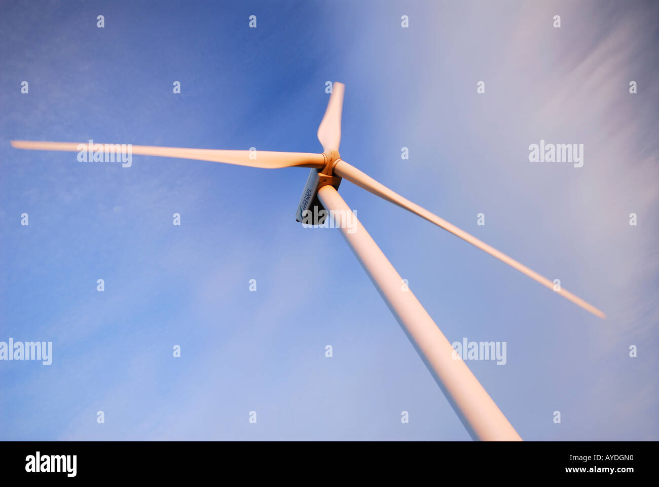 Spinning Blades of a large wind turbine at sundown isolated against sky and clouds Stock Photo