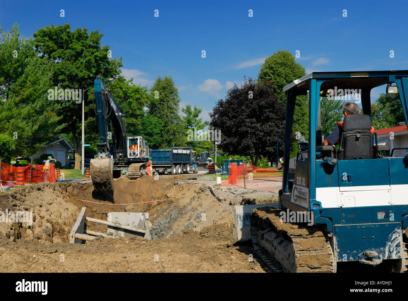 Road construction crew discusses sewer excavation and repair with